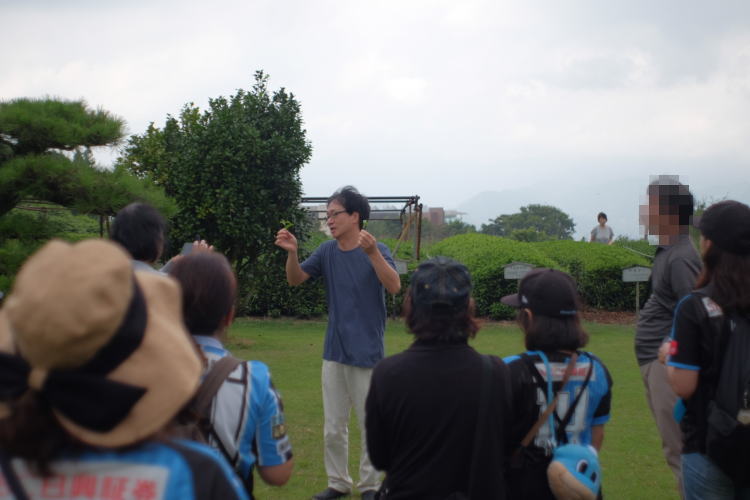 The tea facility manager explaining to his guests how to pick green tea leaves