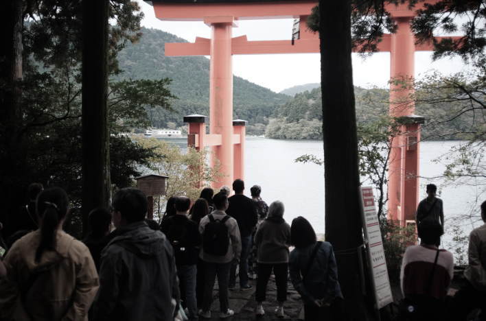 A line of people waiting to take commemorative photos in front of the "Peace Torii" gate at Hakone Shrine.